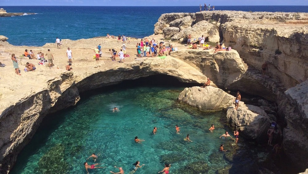 Bagnanti nella Grotta della Poesia, piscina naturale sul mare del Salento